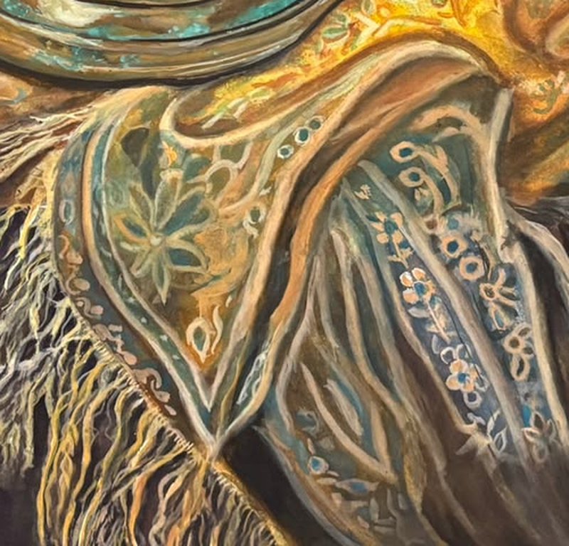 Detail: the shawl's border and fringe hanging over the table edge, patterned with teal leaves and small flowers