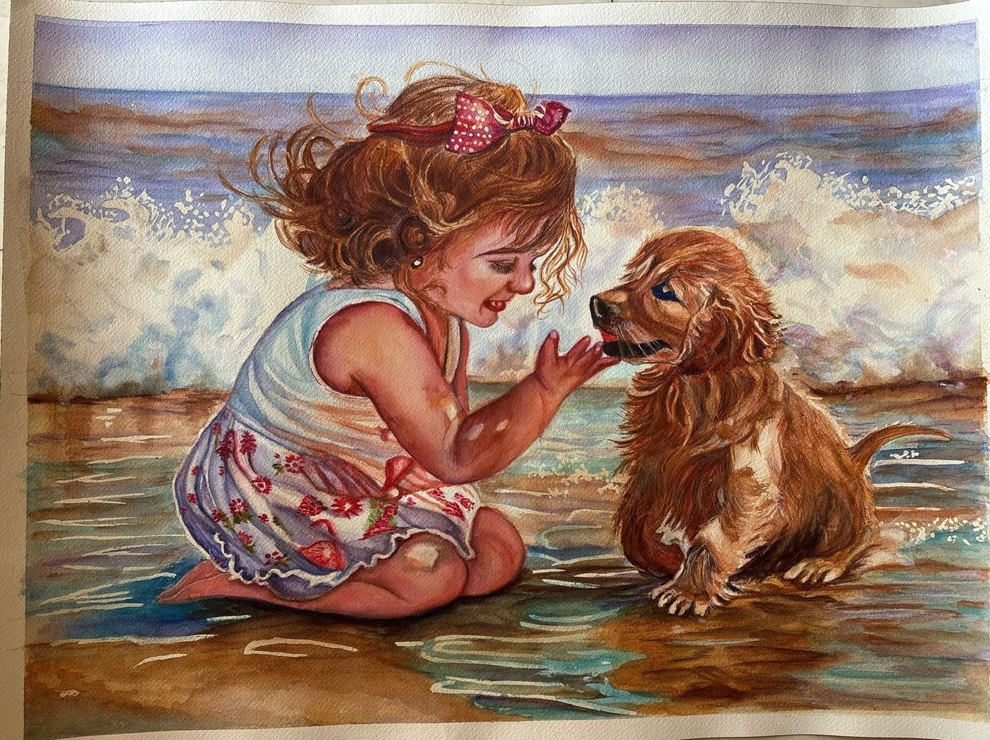 Watercolour by Ujwal Patil: a curly-haired little girl in a floral dress and a pink polka-dot bow kneels at the water's edge, reaching toward a golden puppy, with a white-capped wave behind them