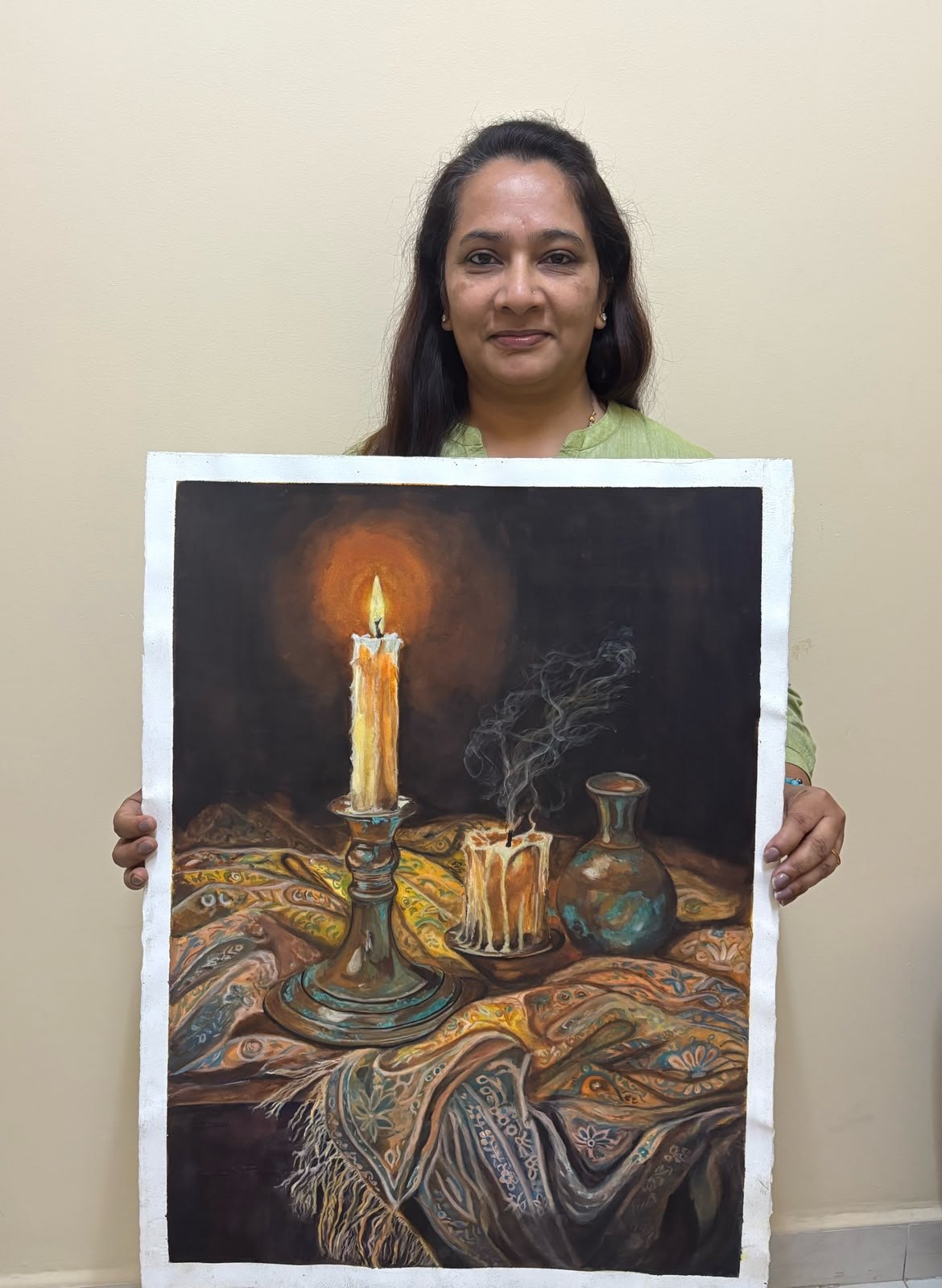Ujwal Patil smiling, holding her finished watercolour Candle Light