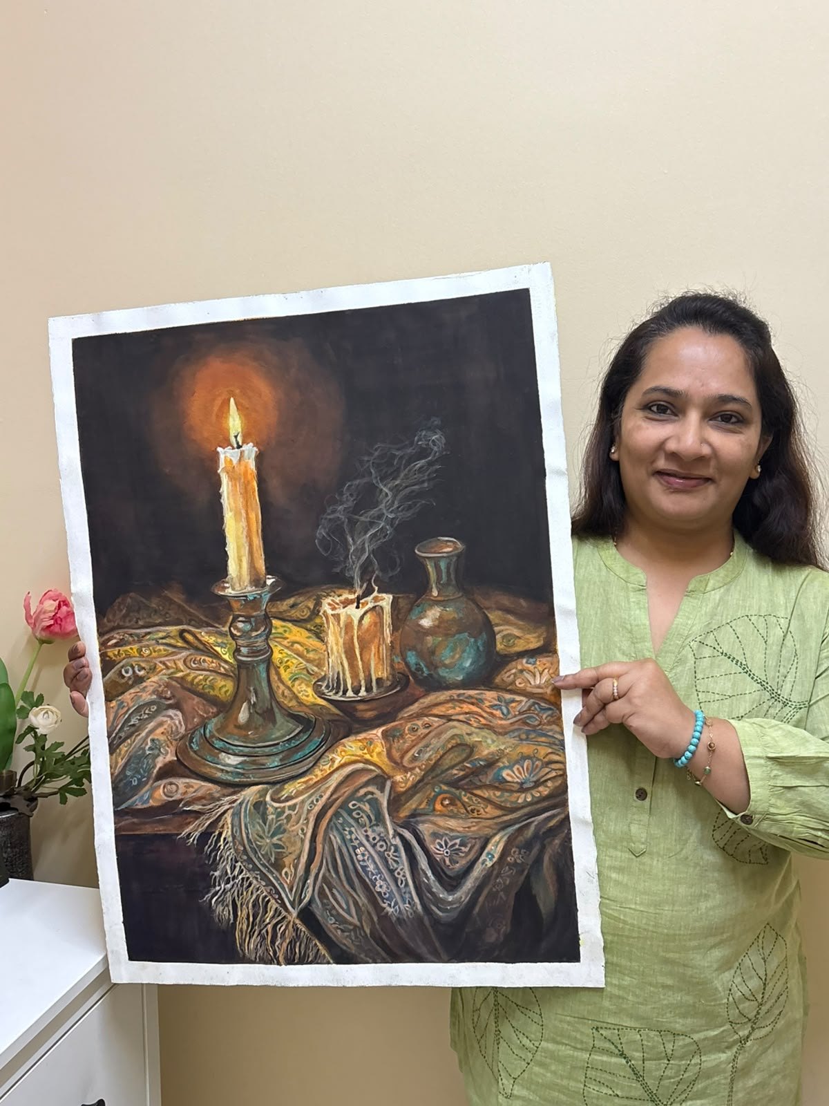 Ujwal Patil smiling, holding her finished watercolour Candle Light in front of her